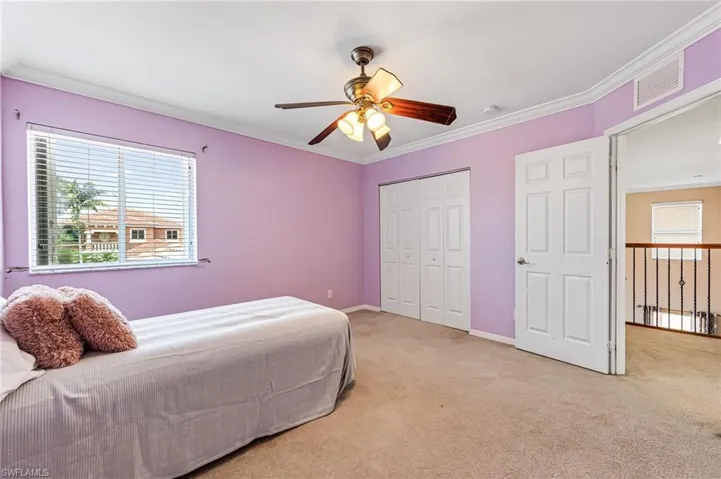 Carpeted bedroom with ceiling fan, a closet, and crown molding