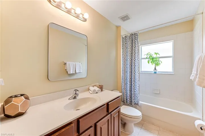 Full bathroom featuring toilet, shower / bath combo with shower curtain, vanity, and tile patterned flooring