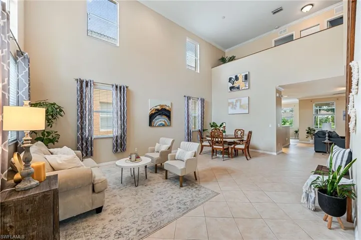 Living room with crown molding, light tile patterned floors, and a htowering  ceiling