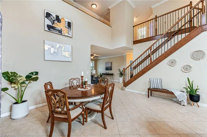 Tiled dining area with ceiling fan, crown molding, and a towering ceiling