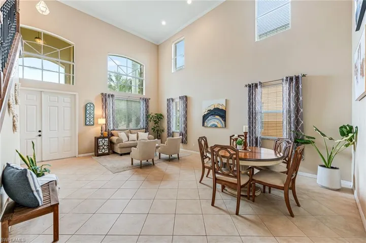 Tiled dining area featuring ornamental molding and a towering ceiling