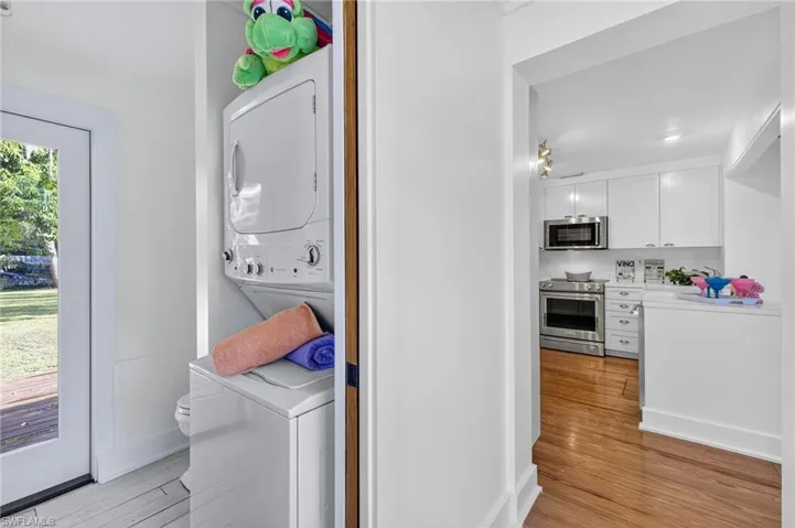 Laundry and 1/2 bath Washroom featuring stacked washer / drying machine and wood flooring
