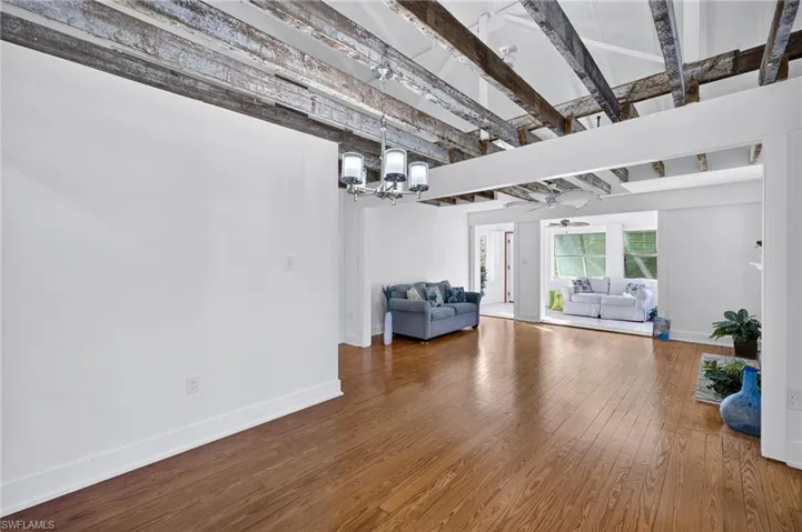 Unfurnished living room featuring , wood finished floors, a ceiling fan, and beam ceiling