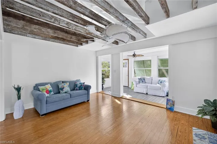 Living area with a ceiling fan, hardwood  floors, and beamed ceiling
