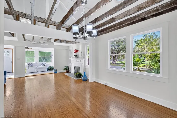 Unfurnished living room with hardwood  floors,  a fireplace, beamed ceiling, and ceiling fan