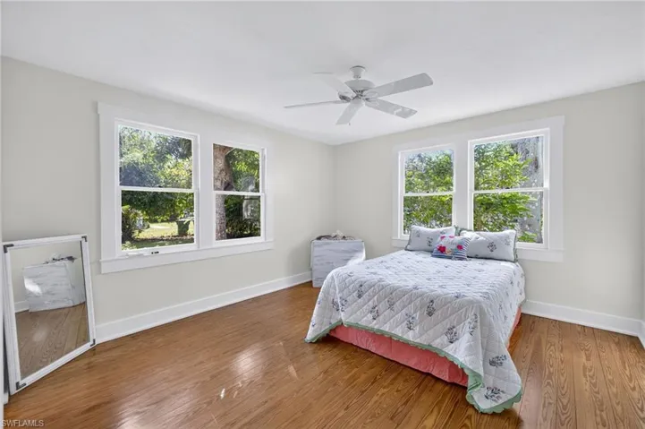 Bedroom featuring multiple windows, wood finished floors, and a ceiling fan