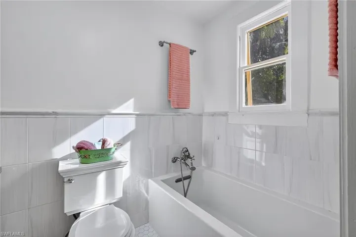 Bathroom featuring tile walls, a bath
