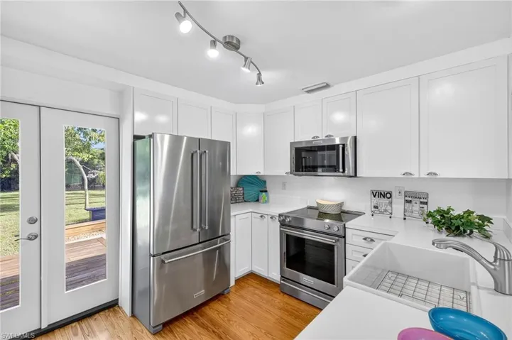 Kitchen featuring stainless steel appliances, light countertops, white cabinets, and wood  flooring
