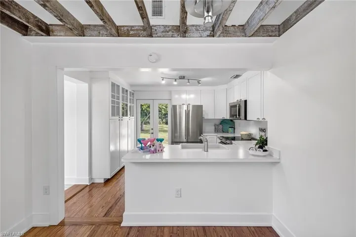 Kitchen featuring a peninsula, stainless steel appliances, light countertops, white cabinetry, and french doors