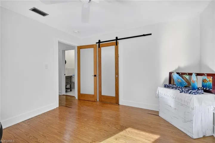 Bedroom with wood finished floors, a barn door, and a ceiling fan