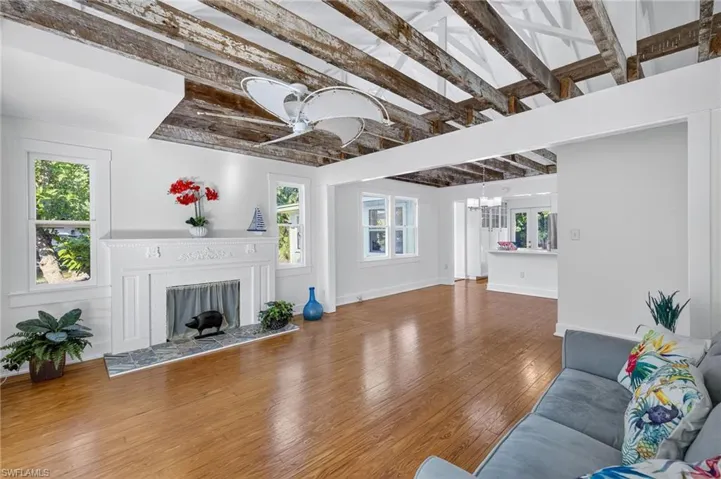 Living room with beamed ceiling, wood finished floors, a fireplace, and healthy amount of natural light