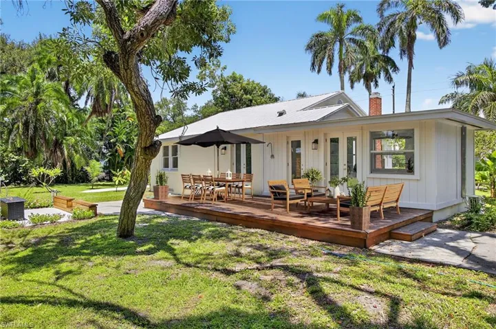 Virtualp Stage Back of property at dusk with a wooden deck, a yard, french doors