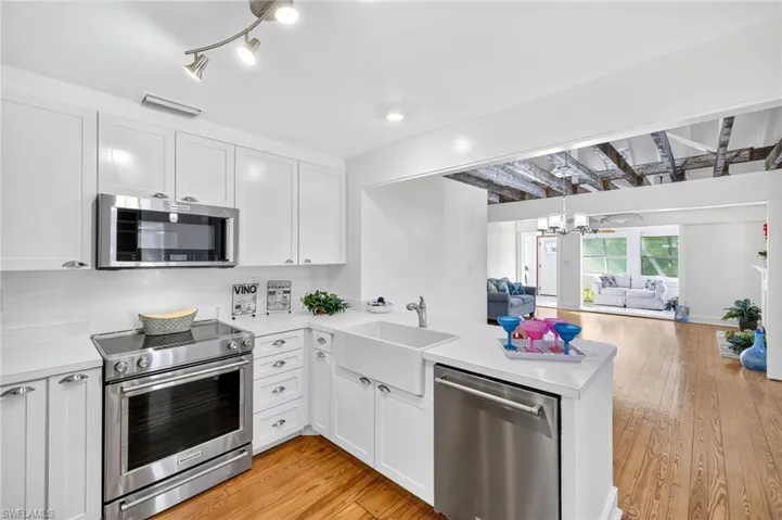 Kitchen featuring appliances with stainless steel finishes, open floor plan, a peninsula, light countertops, and lwood flooring