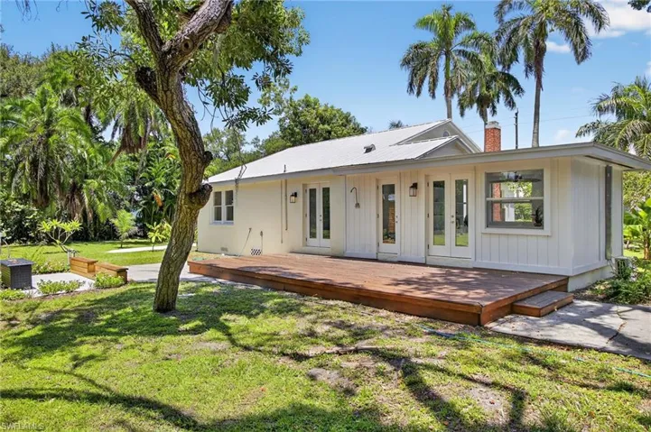 Virtual stage Back of house with french doors, a deck, a chimney, a lawn, and an outdoor hangout area