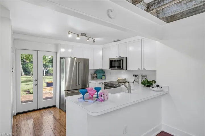 Kitchen with stainless steel appliances, light countertops, white cabinetry, and a peninsula