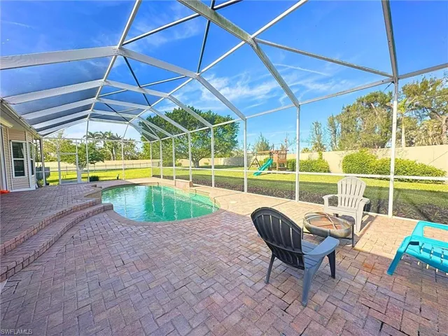 View of swimming pool with a playground, a lanai, a patio area, and a lawn