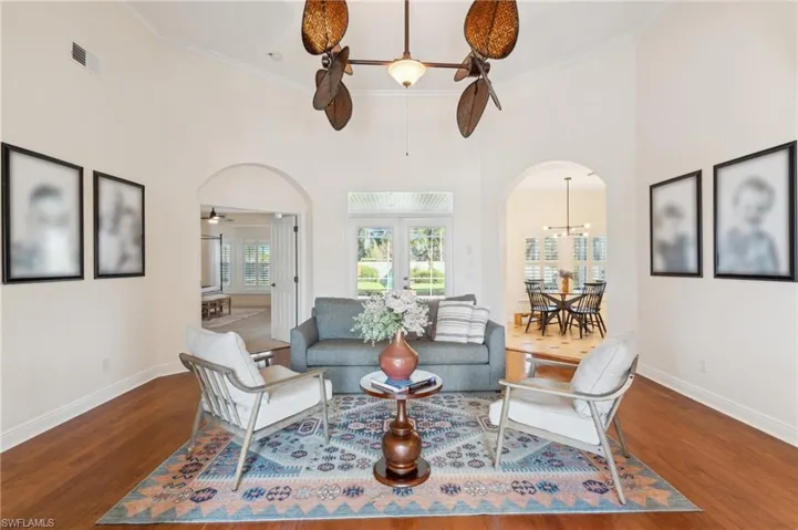 Living room with a towering ceiling, crown molding, ceiling fan with notable chandelier, and dark hardwood / wood-style flooring