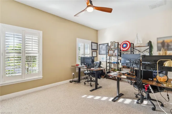 Carpeted office with ceiling fan and a wealth of natural light
