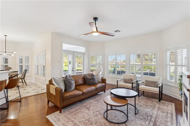 Living room with french doors, wood-type flooring, and ceiling fan with notable chandelier