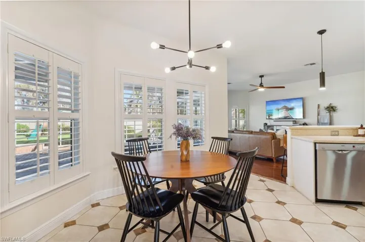 Tiled dining area featuring ceiling fan with notable chandelier and plenty of natural light