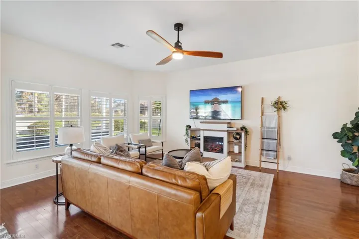 Living room with ceiling fan and dark hardwood / wood-style flooring