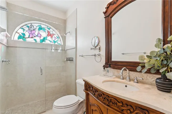 Bathroom featuring vanity, toilet, and a shower with door