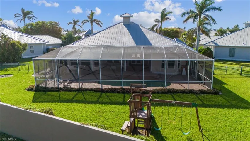Rear view of property with a yard, a patio area, and glass enclosure