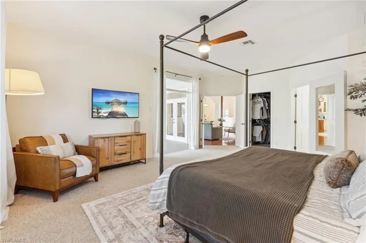 Bedroom featuring a spacious closet, light carpet, a closet, and ceiling fan