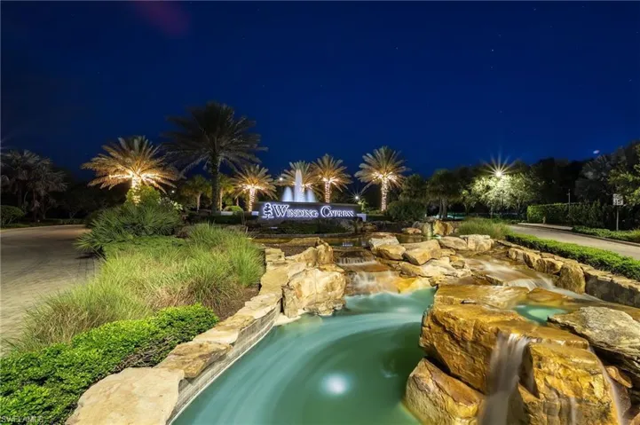 Winding Cypress entrance featuring a stone water fountain with multiple cascades and accent lighting.