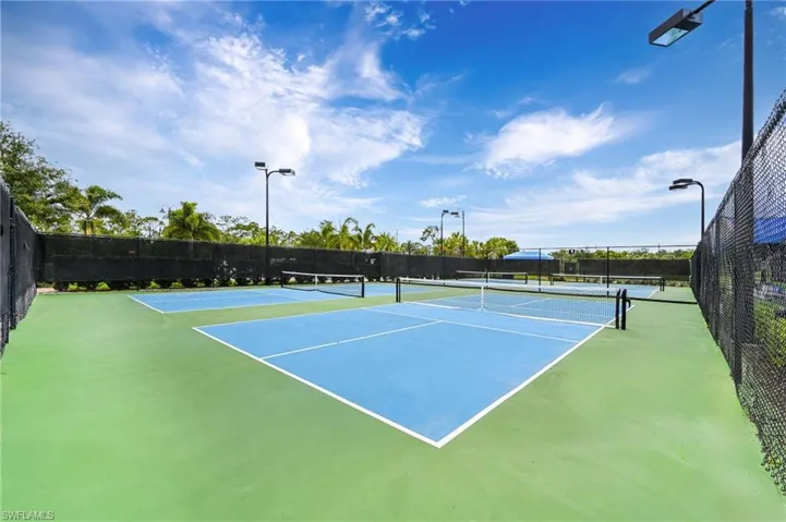 Multiple outdoor courts with blue playing surfaces and green surrounds