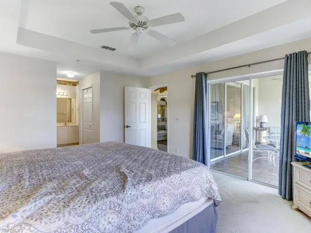 Carpeted bedroom with access to outside, a ceiling fan, and a raised ceiling
