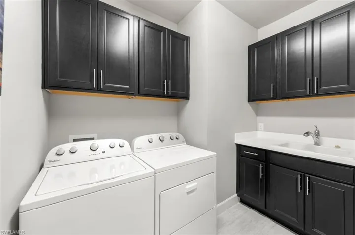 Oversized laundry room fitted with closets and sink.