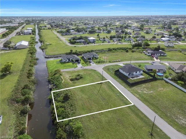Expansive canal-front lot featuring a grassed area, mature foliage, and direct water access