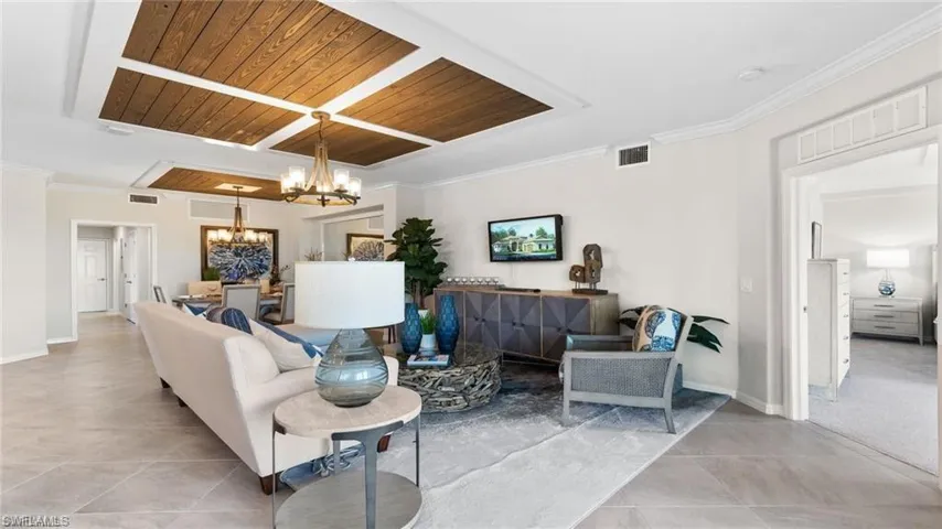 Living area featuring a chandelier, tile patterned floors, wooden ceiling, baseboards, and ornamental molding