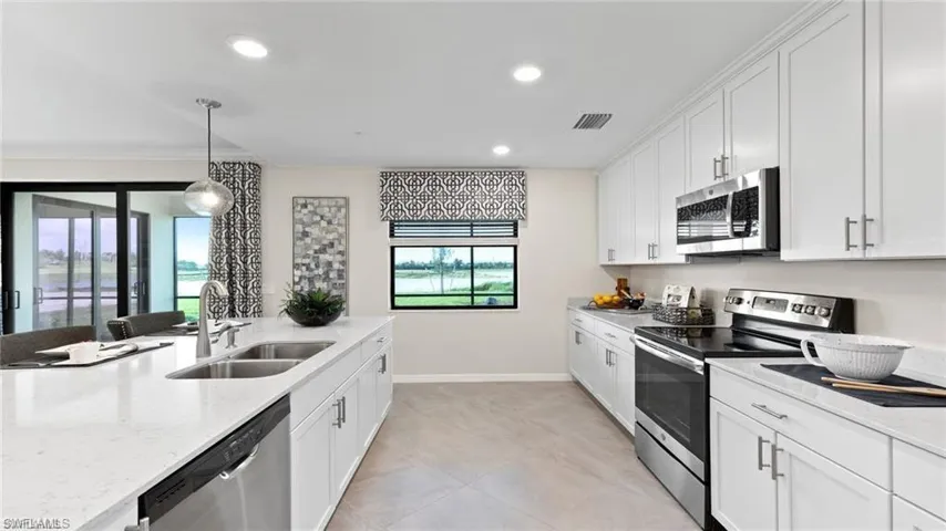 Kitchen with stainless steel appliances, a sink, white cabinetry, recessed lighting, and light stone counters