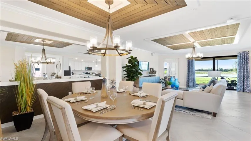 Dining space with a chandelier, wooden ceiling, light tile patterned flooring, a tray ceiling, and ornamental molding
