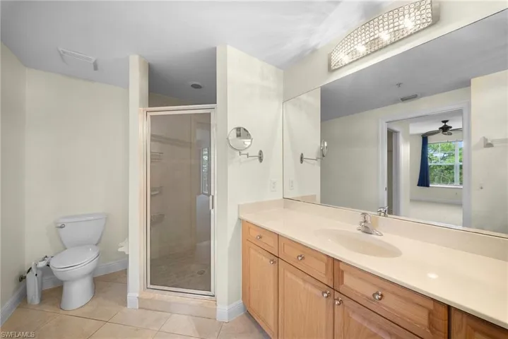 Full bathroom featuring a single vanity with wood-finish cabinetry, a light-colored countertop, and an integrated sink