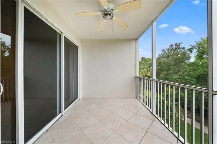 Screened balcony featuring tiled flooring, a ceiling fan, and sliding glass doors