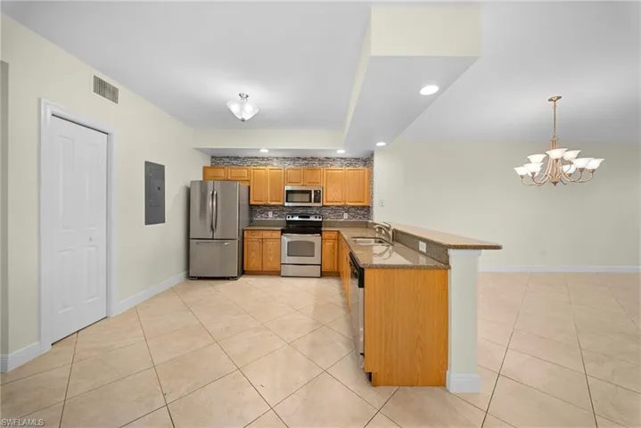 Kitchen featuring wood cabinetry, stainless steel appliances, granite countertops, and a stone-finish backsplash