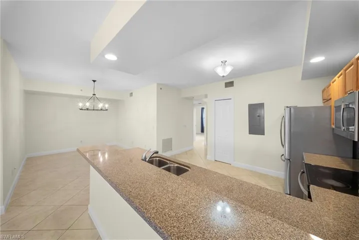 Kitchen island featuring a double-basin sink and speckled countertop