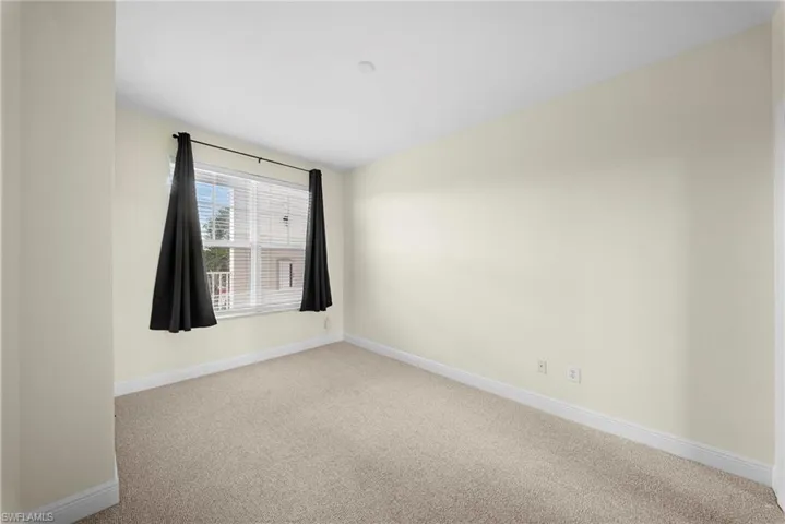 Inviting room featuring a large window, neutral wall tones, and plush carpeting
