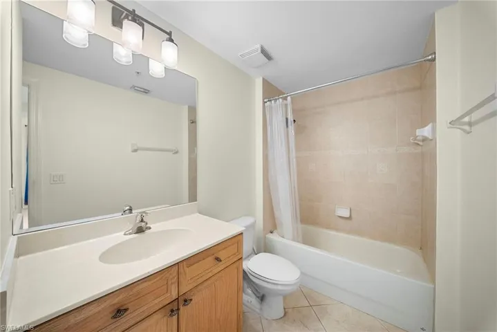 Full bathroom featuring a wood-finish vanity with an integrated sink, a large wall mirror, and an overhead vanity light fixture