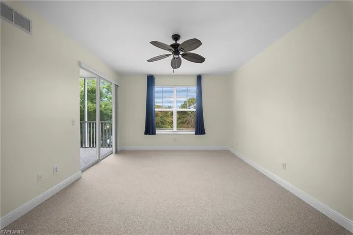 Spacious room featuring neutral carpeting, a ceiling fan, and white baseboards