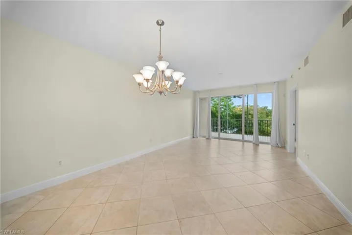 Open-concept living area with large format tile flooring and a multi-light chandelier