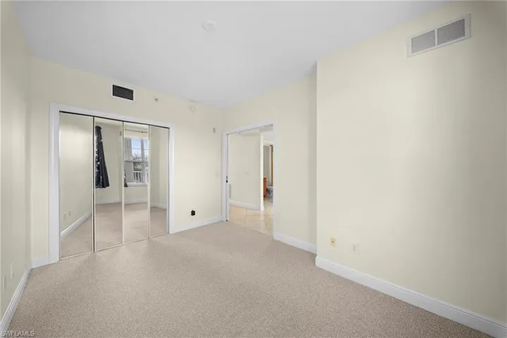 Spacious room featuring neutral carpeting, light-toned walls, and white baseboards