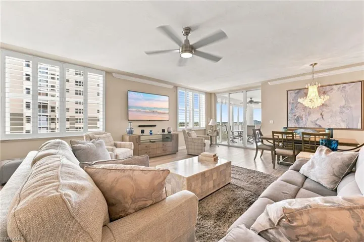 The stunning main living area showcases breathtaking views of the Caloosahatchee River and marina, complemented by beautiful new luxury vinyl flooring, elegant crown molding, and a striking chandelier that adds a touch of glamour to the dining area.