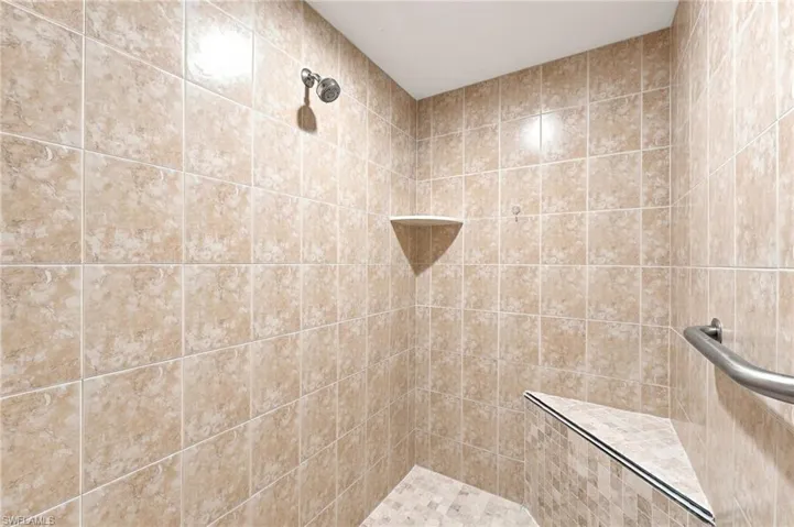 The luxurious primary bath features a spacious walk-in shower with a built-in seating area and elegant floor-to-ceiling tile, creating a sophisticated and spa-like retreat.