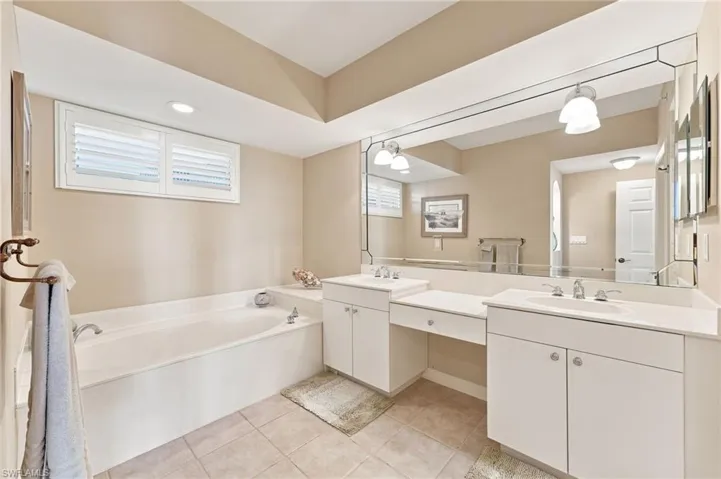 The luxurious primary ensuite bath features dual vanities, a dedicated dressing area, a separate soaking tub, and a spacious walk-in shower. Abundant natural light fills the space, creating a bright, serene, and beautifully inviting retreat.