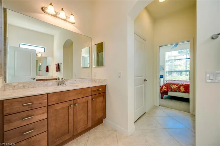 Ensuite bathroom featuring healthy amount of natural light, vanity, and light tile patterned flooring