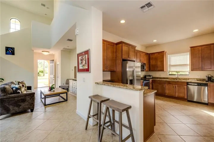 Kitchen with a peninsula, healthy amount of natural light, light stone countertops, recessed lighting, and a towering ceiling